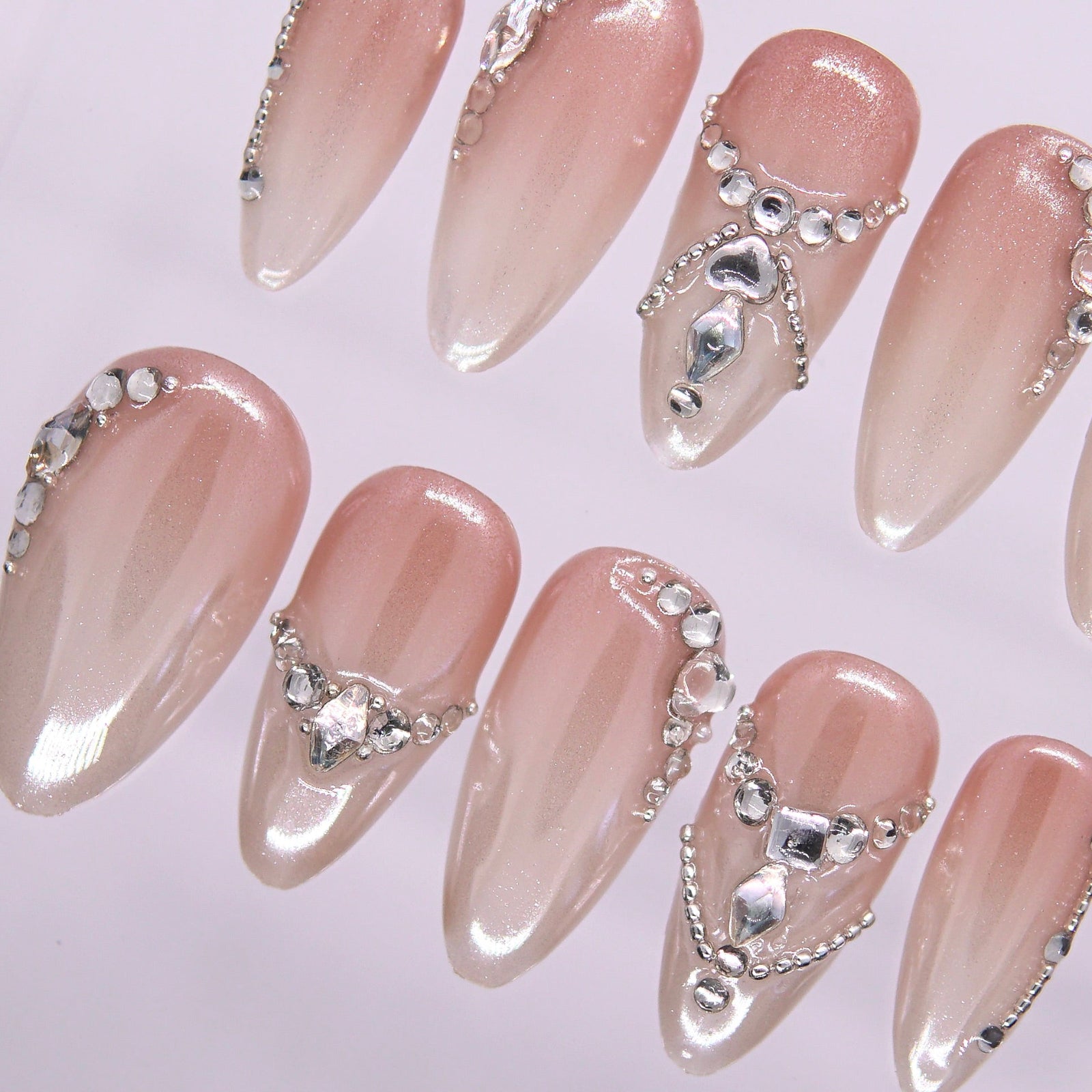 Close-up of crystal accents on glossy nude press-on nails