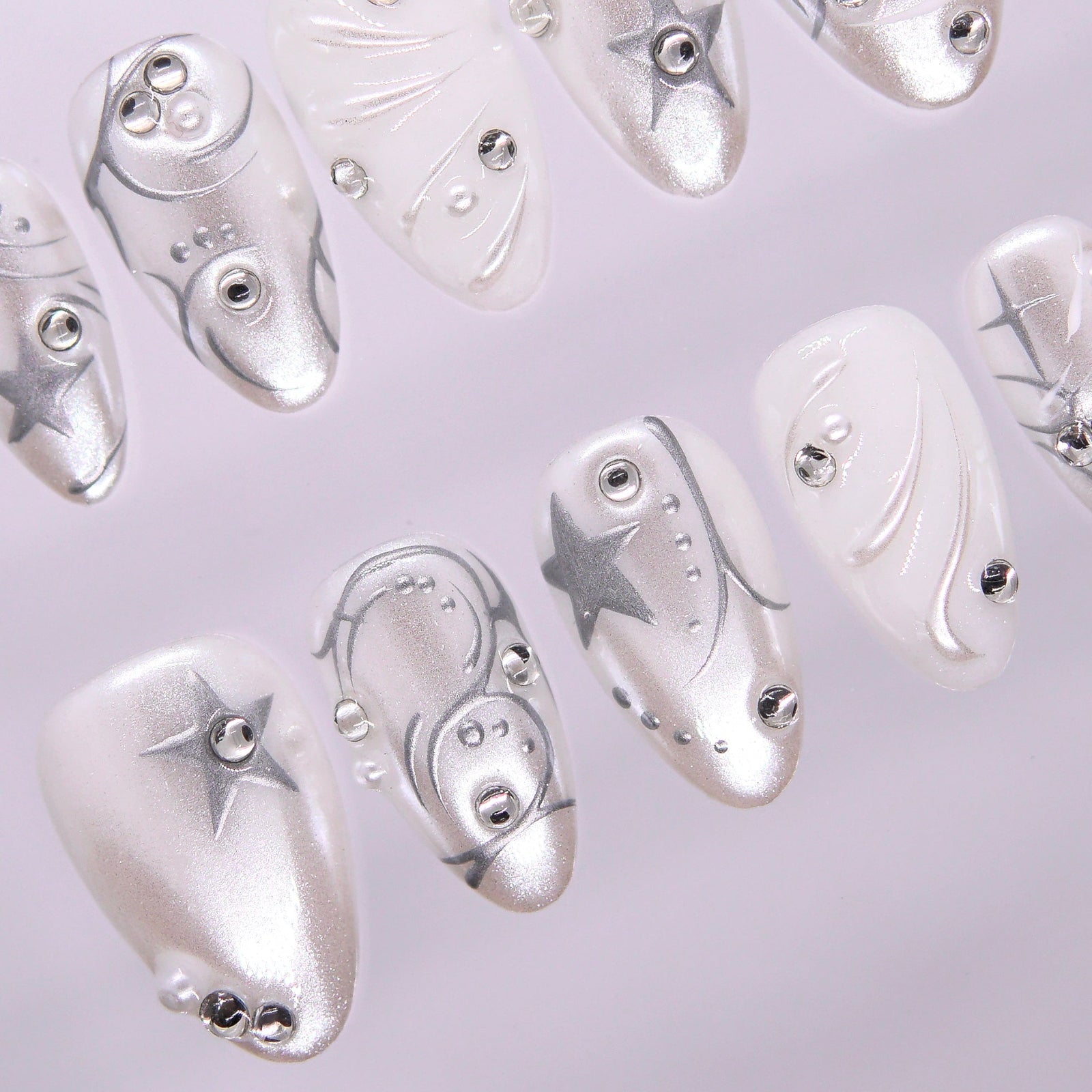 Glossy chrome silver and pearly white press-on nails with futuristic star details.