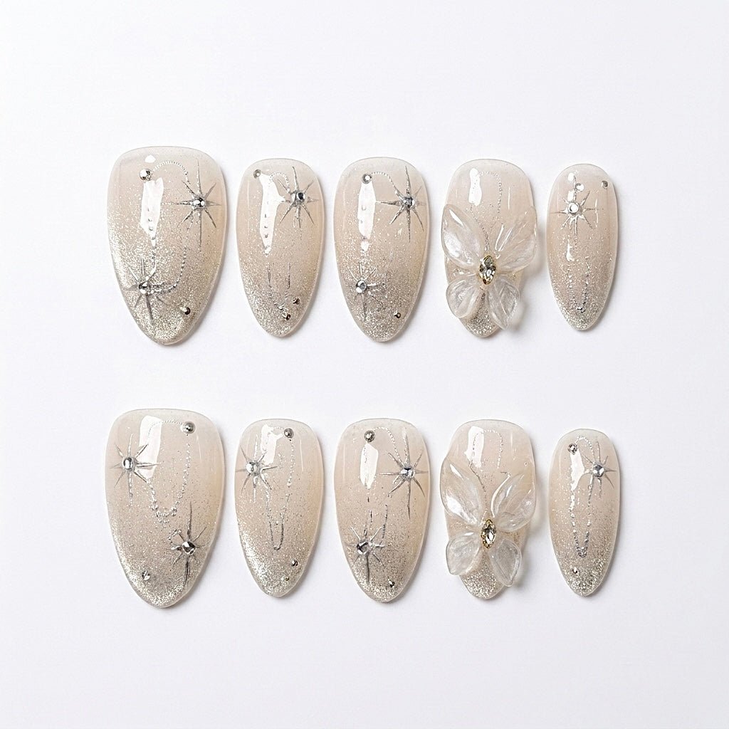 Starlight Bloom handmade press-on nail set with champagne shimmer, silver starburst details, crystals, and translucent sculpted flowers by Nailsium