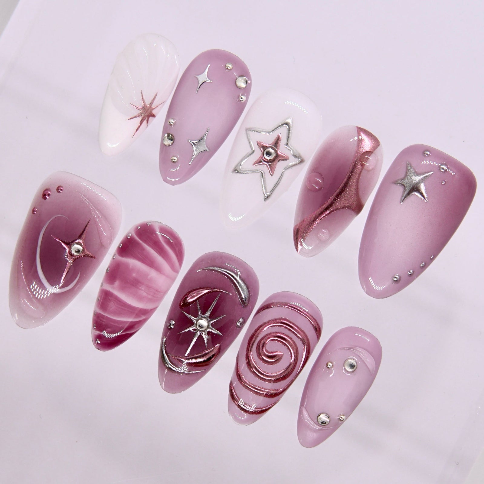 Close-up of Starlit Orbit nails showing metallic swirl and cosmic embellishments.