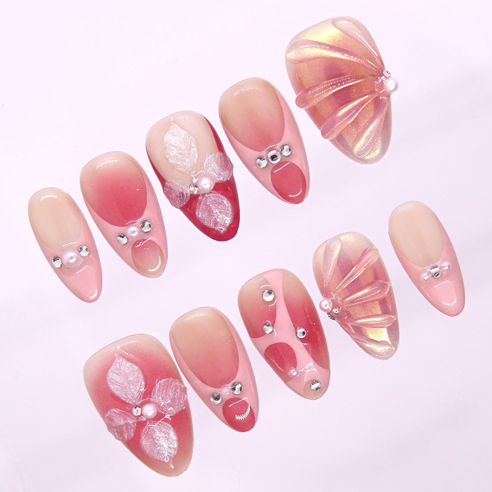 Close-up of pearly petals and warm peach-pink gradient on sunset-inspired press-on nails.