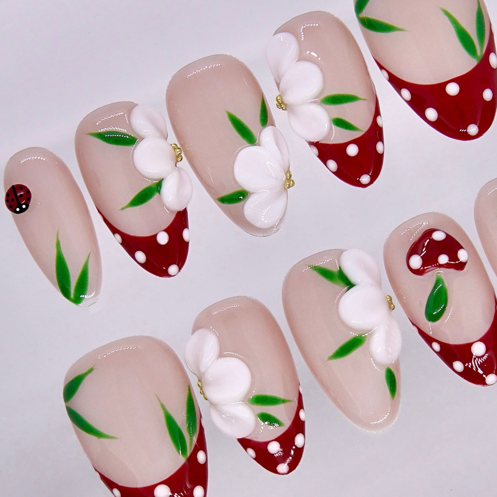 Cute nail design with floral patterns, ladybug detail, and glossy finish