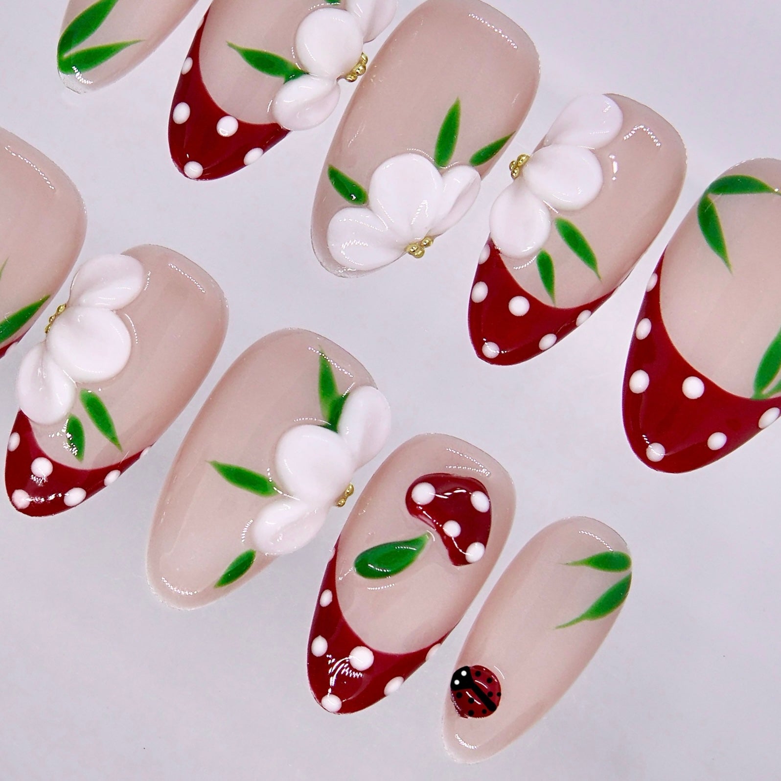 Cute nail design with floral patterns, ladybug detail, and glossy finish