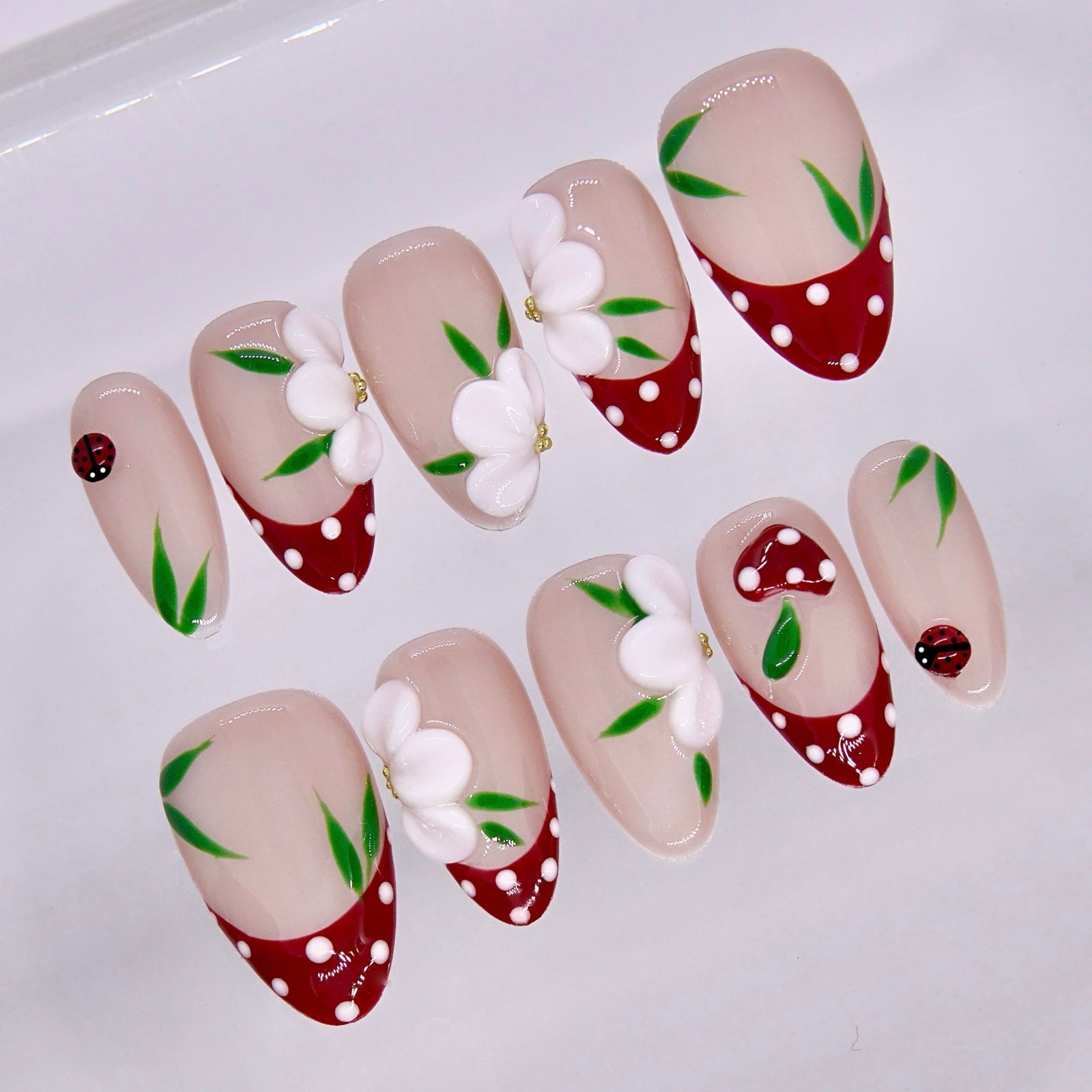 Close-up of red tip nails with white dots and small flower accents