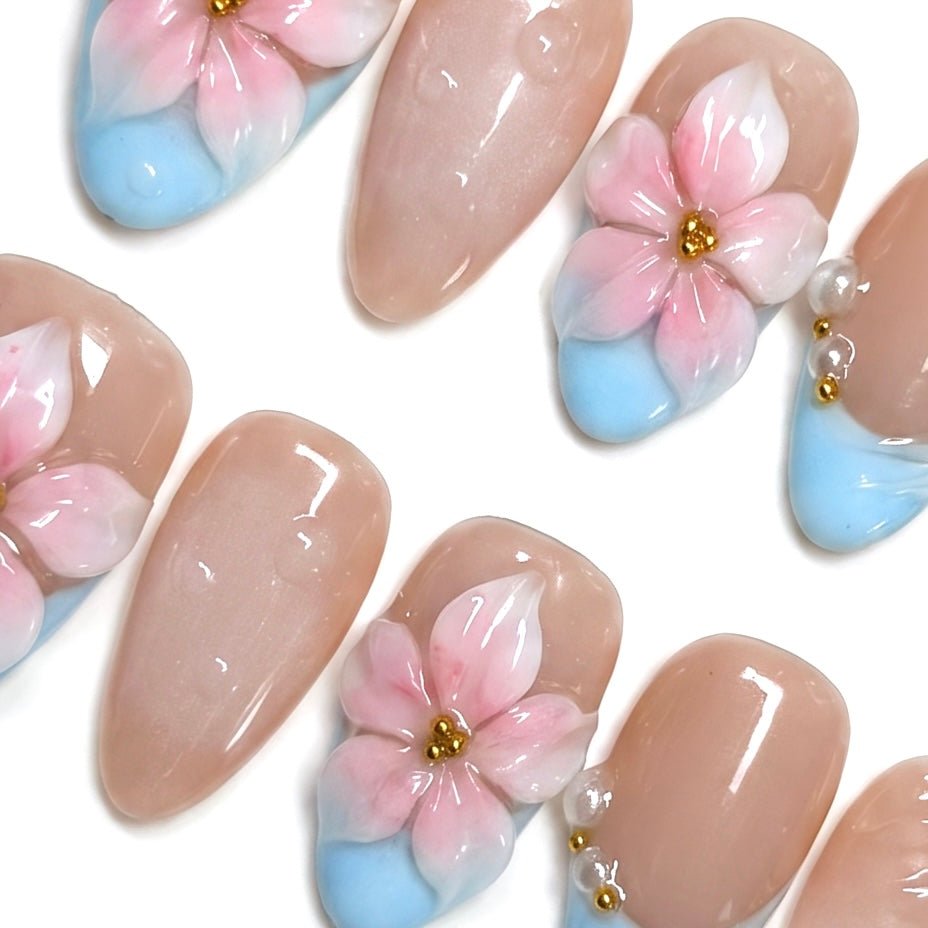 Almond shaped floral press on nails with glossy nude base.