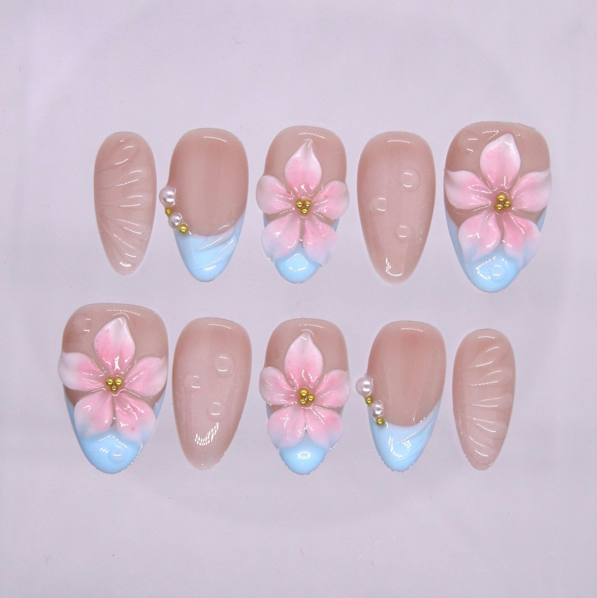 Blue French tip press on nails with 3D pink flowers and pearl embellishment.
