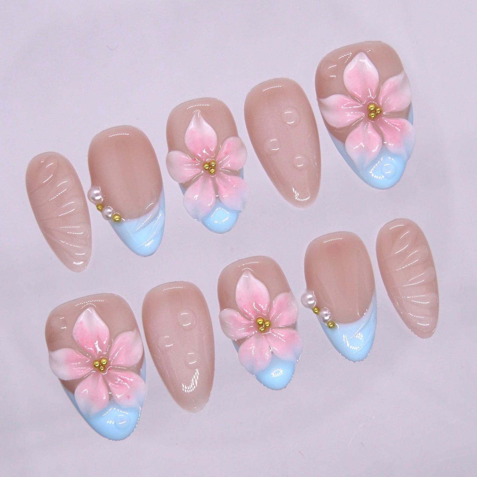 Close up of baby blue French tip with sculpted pink flower and gold bead center.
