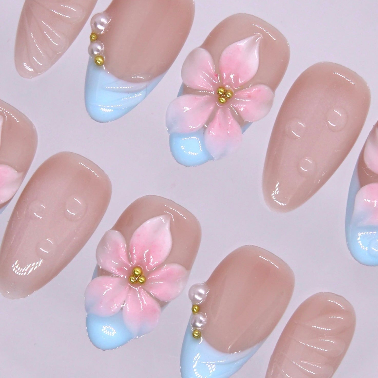 Almond shaped floral press on nails with glossy nude base.