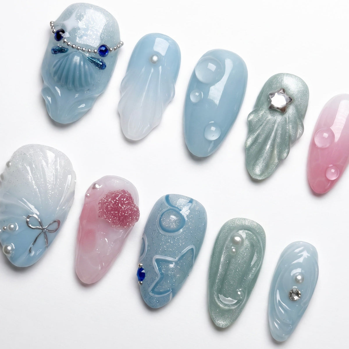 Tidepool Walk press-on nails with soft seafoam-to-pink gradient, featuring iridescent shell pieces, silver star glitters, and water droplet accents — part of the La Jolla · Water · Flow collection.