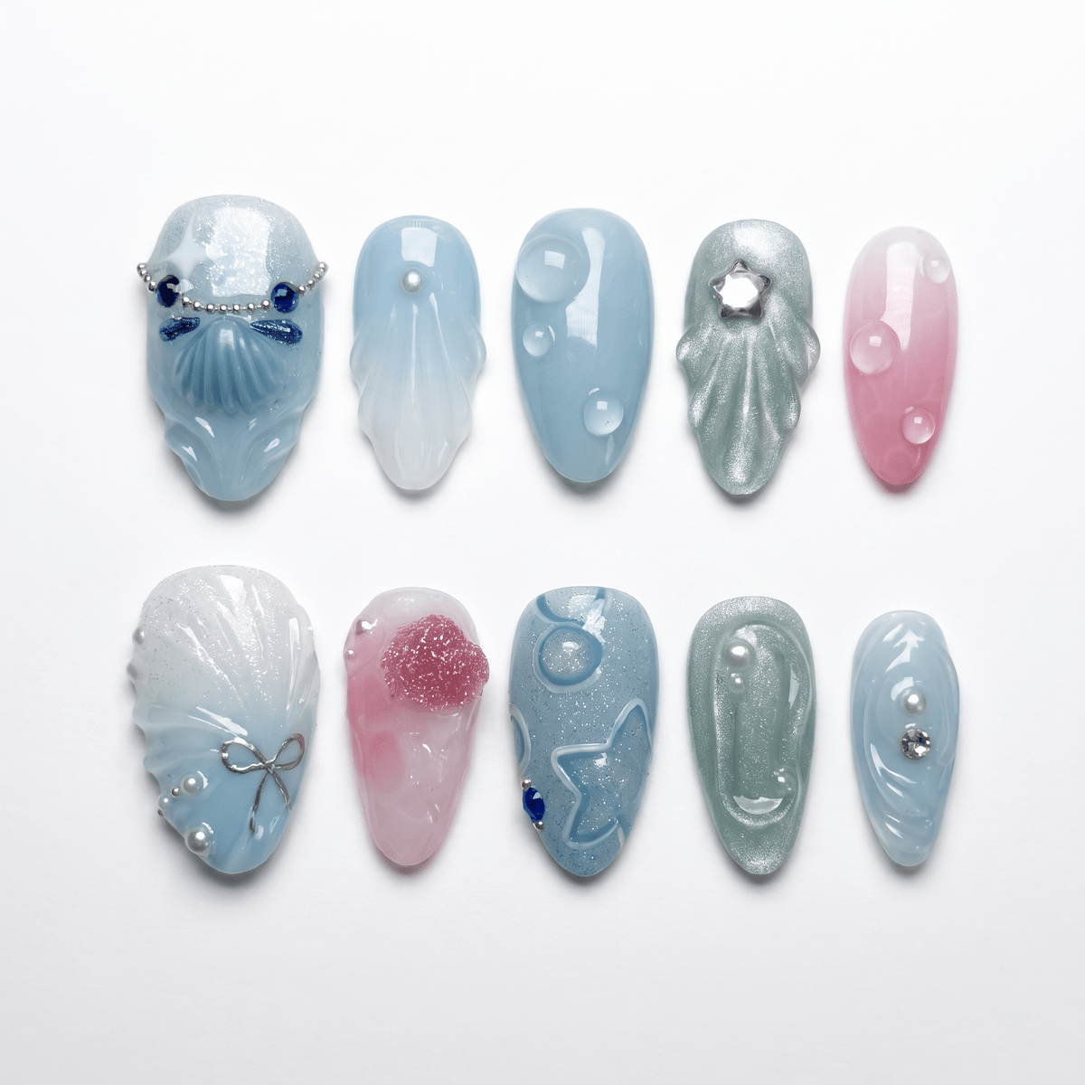 Tidepool Walk press-on nails with soft seafoam-to-pink gradient, featuring iridescent shell pieces, silver star glitters, and water droplet accents — part of the La Jolla · Water · Flow collection.