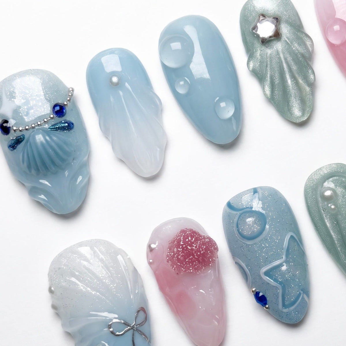 Close-up of translucent nail with seashell shard and silver microchain, capturing a tidal treasure vibe.