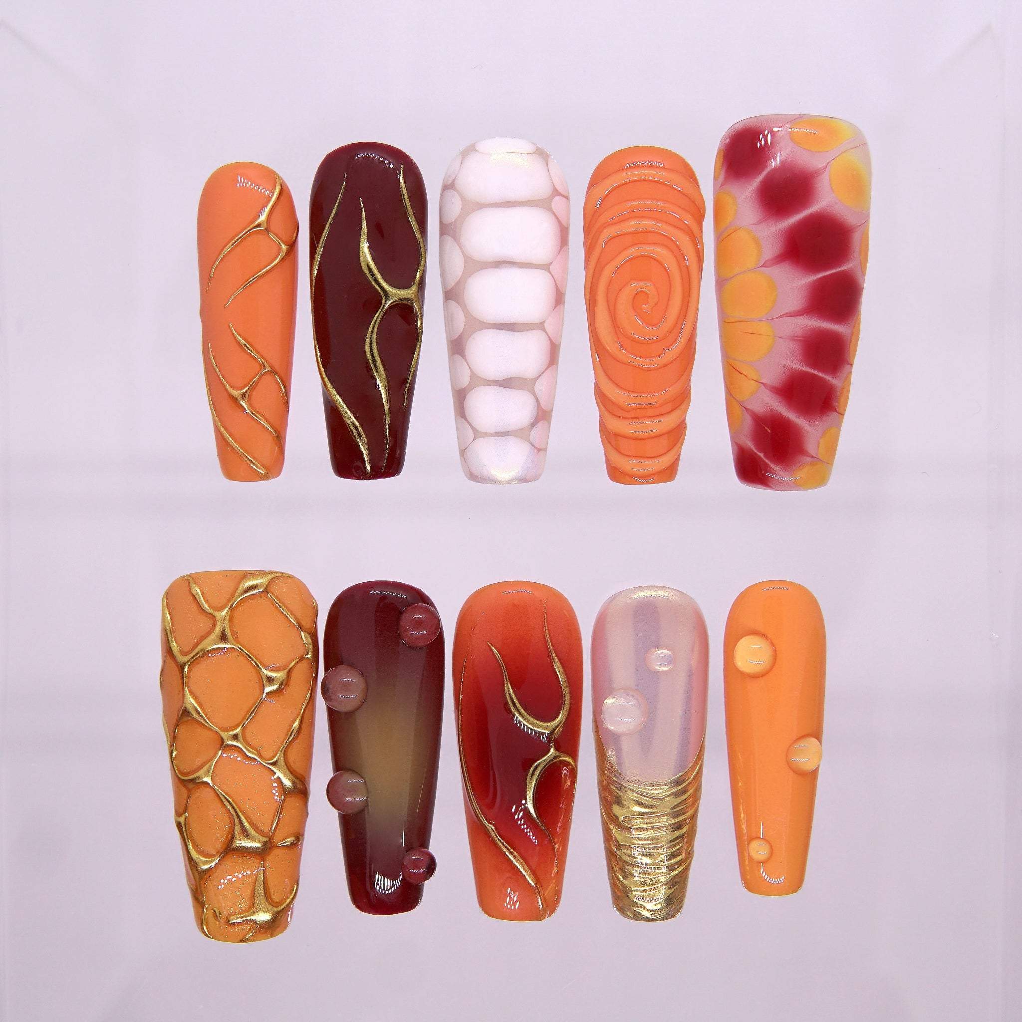 Top view of Torrey Burn press-on nails featuring orange-red ombré base with gold fire-like veins and 3D droplets, inspired by La Jolla’s Torrey Pines sunsets.