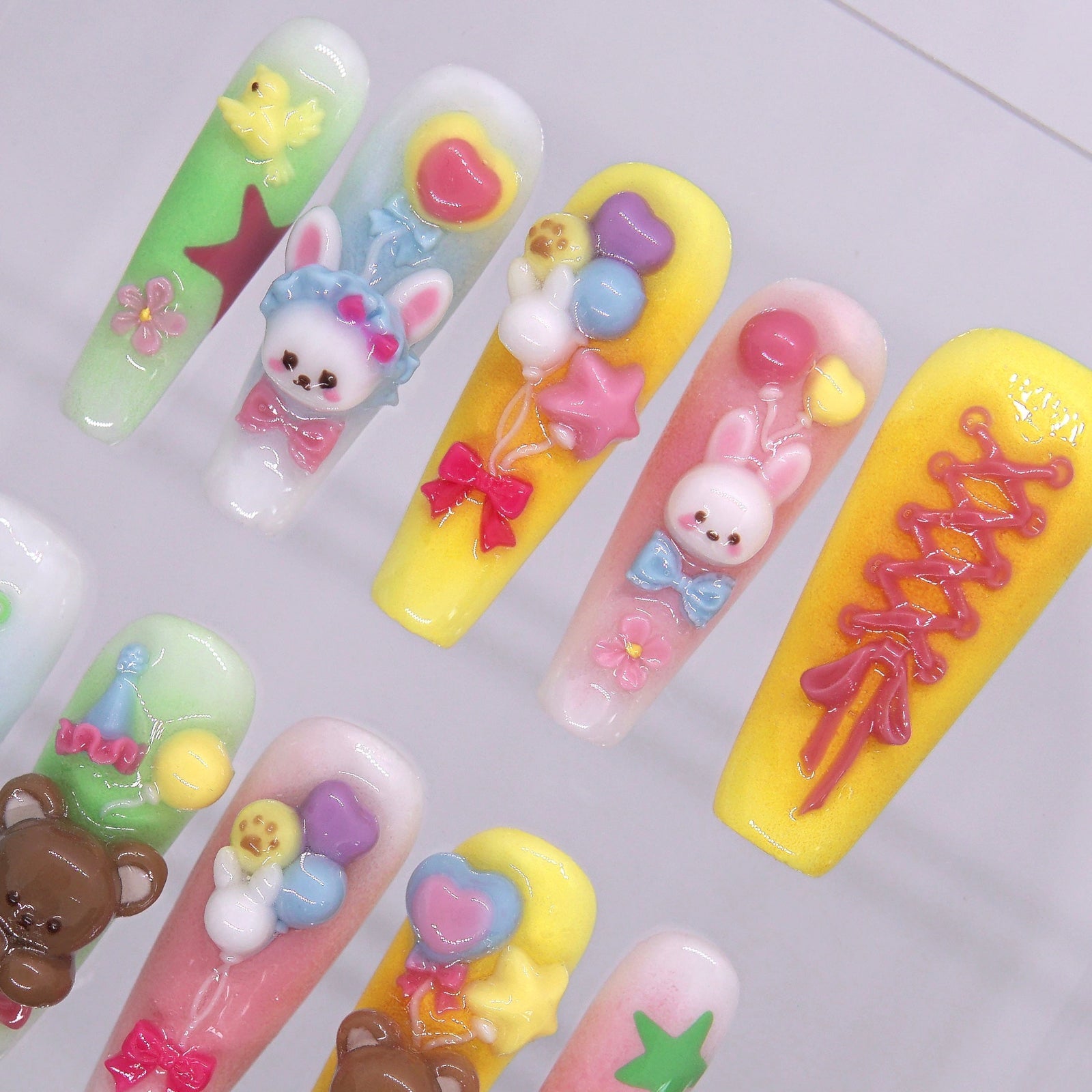Yellow, pink, and green pastel gradient press-on nails with lace-up and star details.