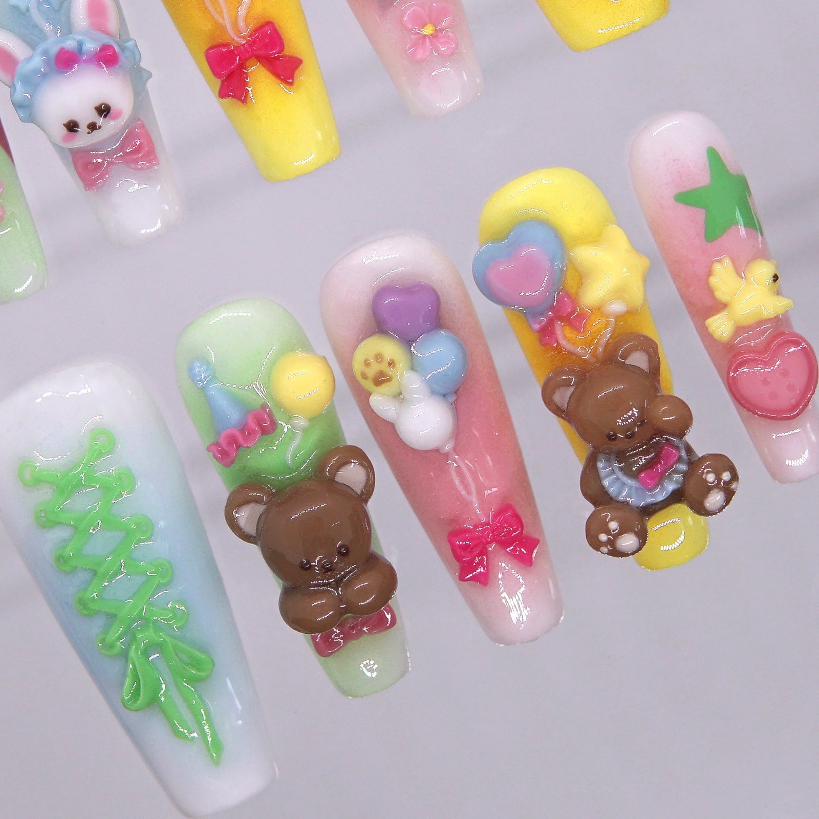 Yellow, pink, and green pastel gradient press-on nails with lace-up and star details.