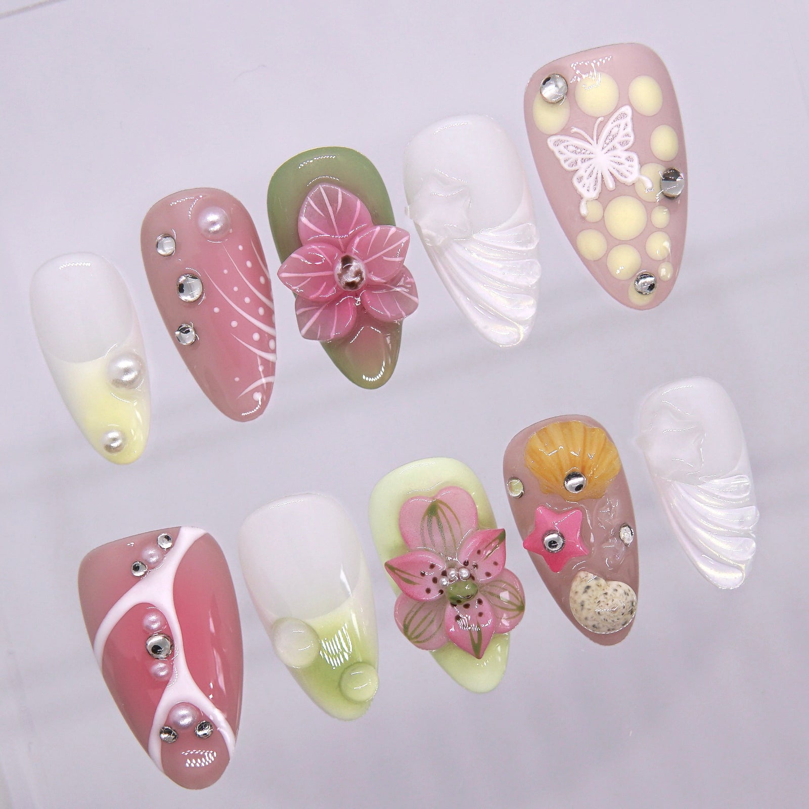 Close-up of tropical 3D pink flowers and green leaves on press-on nails.