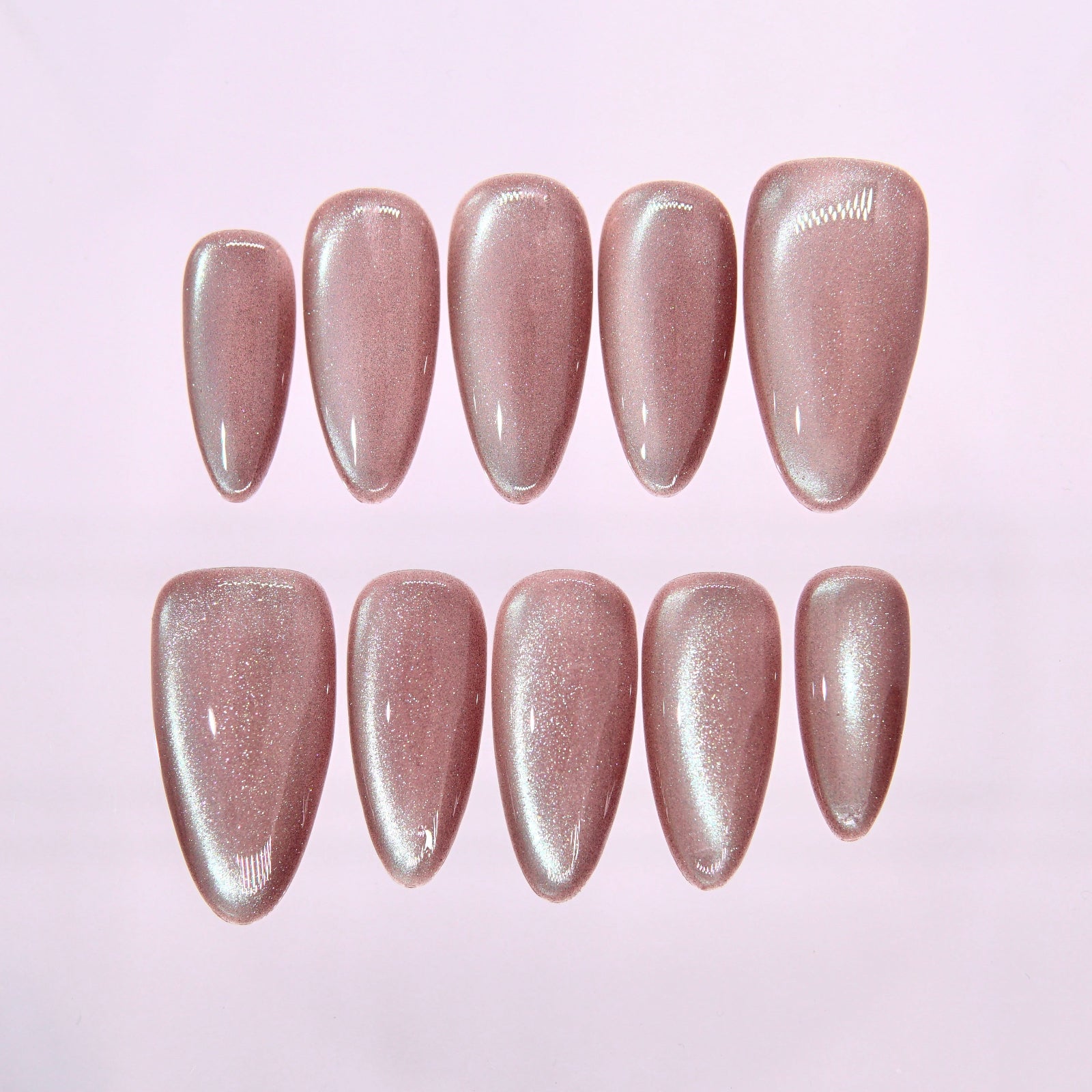 Sheer rosy pink cat eye press on nails arranged on clear display board with soft shimmer