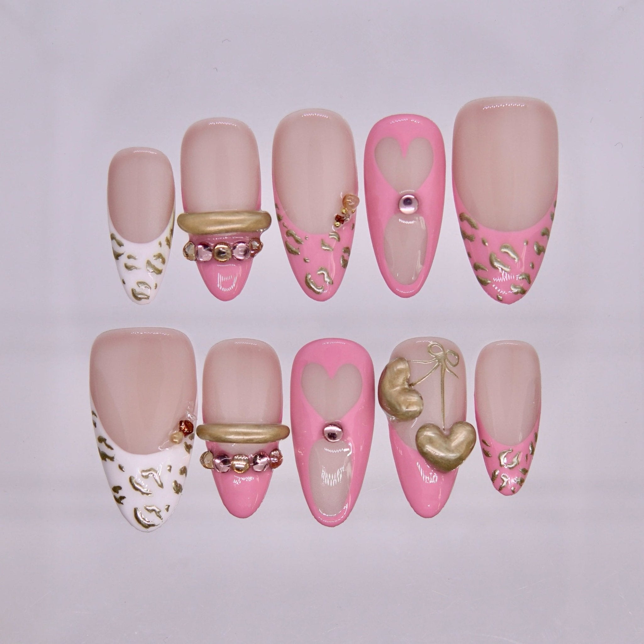 Tiger zodiac press-on nails in nude and blush pink tones with heart accents and sculptural gold details representing Valor self love energy.