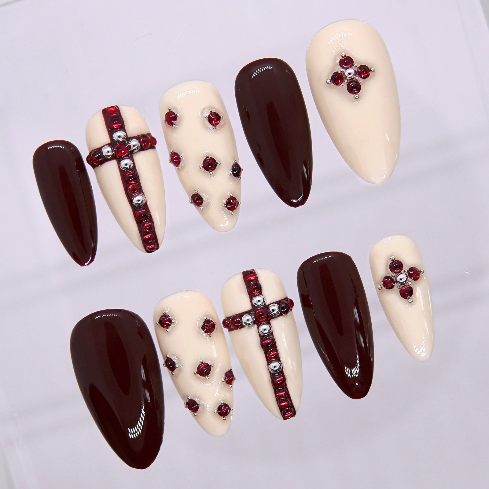 Close-up of handcrafted red gem cross on nude press-on nail